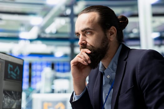 Male factory consultant observes production systems on a pc in a solar plant, providing expert feedback on efficiency, safety and sustainability aligned with green energy initiatives.