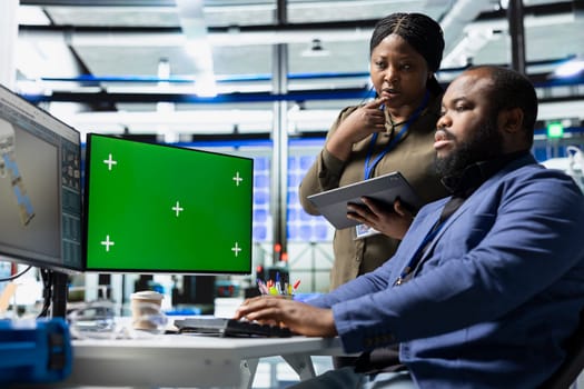 Black engineering team reviewing solar panels next to chroma key, showcasing unity in green technology and eco friendly renewable energy. Operational leadership in manufacturing industry.