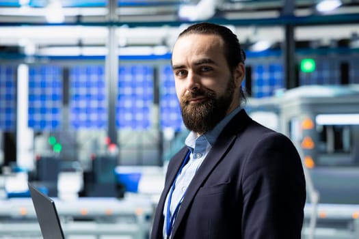Factory inspector in a suit monitoring solar panel production output, reflecting professional occupation and executive level involvement in renewable energy development. Solar power.