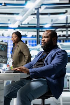 Black clean energy technician in suit checks solar panel alignment, representing the skilled workforce behind industrial operations for renewable energy development and production.