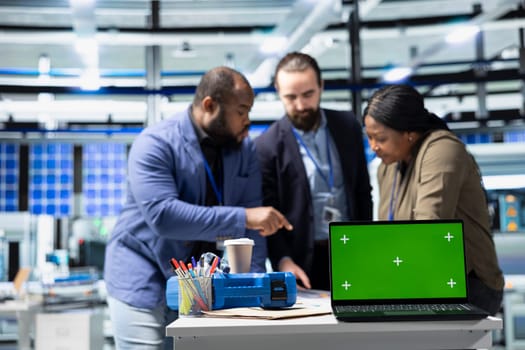 Coworkers brainstorming solutions with mockup display in solar plant, advancing industrial goals through collaboration and corporate responsibility. Team of engineers share insight.