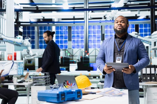 African american supervisor talking to his coworkers and associates in a meeting, sharing insight on the assembly and production line. Reviewing sustainable solutions for energy industry.