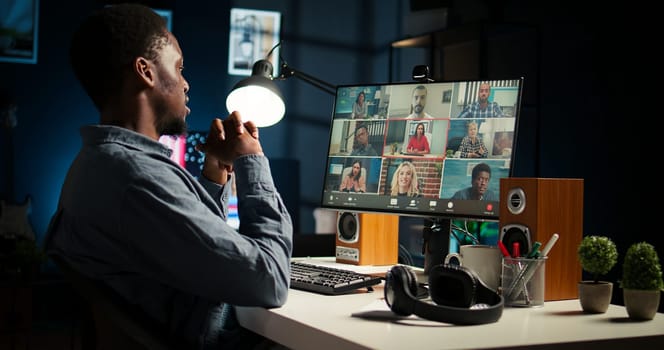 African American man and associates attending a virtual meeting call in his loft, discussing and communicating through a video conference, doing remote work at home. Camera A.