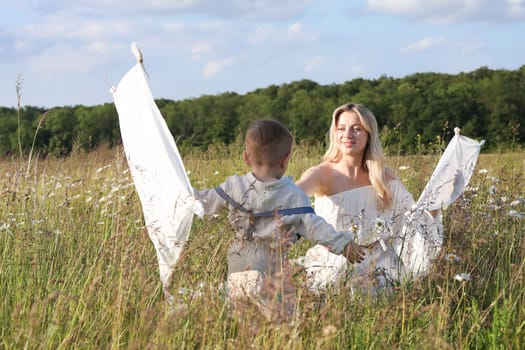 Beautiful young mother and child flying a kite in the meadow. High quality photo