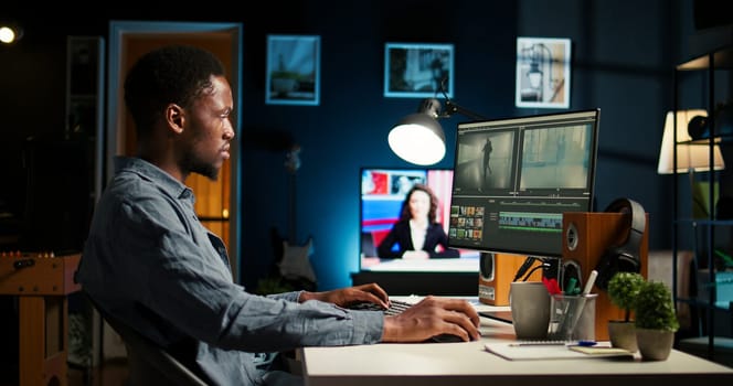 Young man video editor works on editing film footage at home setup, doing freelance contract for post production scenes. Editor correcting white balance and color grading, pc software. Camera A.