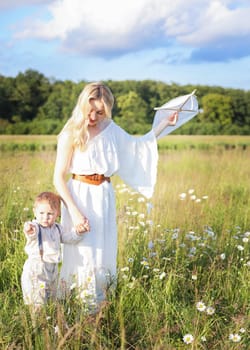 Beautiful young mother and child flying a kite in the meadow. High quality photo