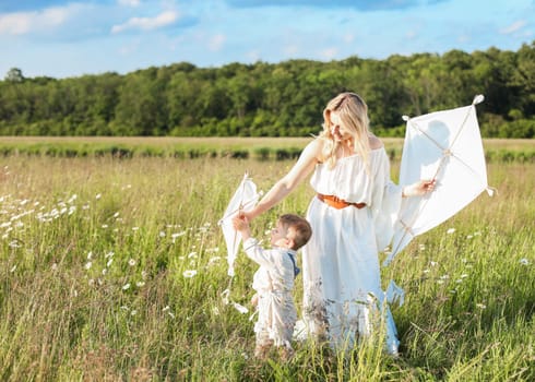 Beautiful young mother and child flying a kite in the meadow. High quality photo