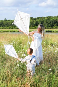 Beautiful young mother and child flying a kite in the meadow. High quality photo