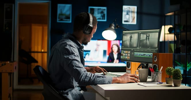 Focused male editor working on video montage in a creative software at home office setup, digital media content. Filmmaker using dual monitors to edit footage in post production. Camera A.