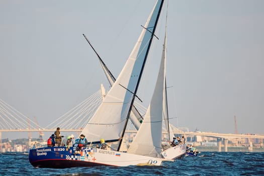 Russia, St.Petersburg, 07 June 2024: Sailing regatta in the Gulf of Finland at sunset, hot race of several yachts, teamwork, yachtsmen sitting on board the boat. High quality photo