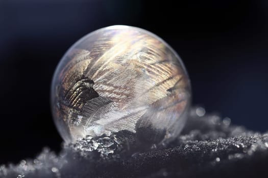 A frozen soap bubble with a pattern in the cold snow