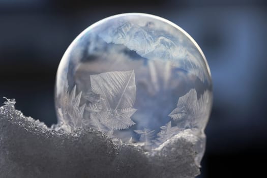 A frozen soap bubble with a pattern in the cold snow