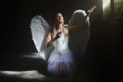 A woman dressed as an angel in the beam of light from a crypt window