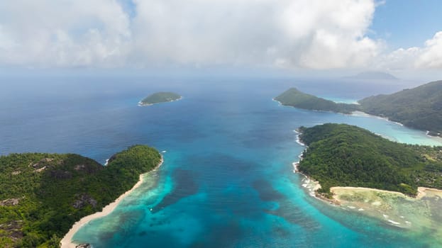 Golden sands along the island's beach with clear waters and tropical vegetation. Seychelles, Mahe.
