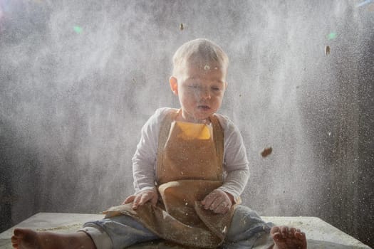 A boy explores the texture of flour while playing in a studio, showcasing a fun and creative cooking activity.