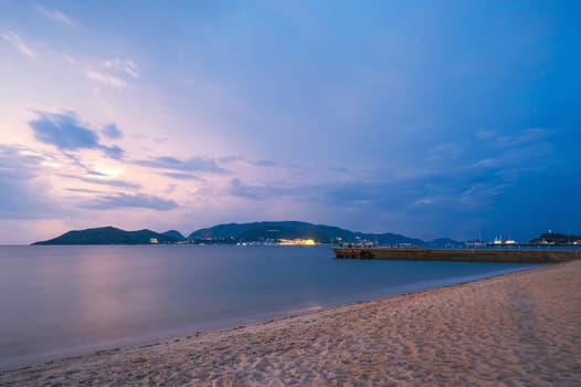 Pier in the sea at the sandy beach at dawn in morning. View of Vinpearl Island in Nha Trang in Vietnam
