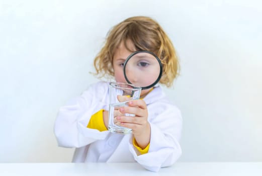 A child examines water with a magnifying glass. Selective focus. kid.