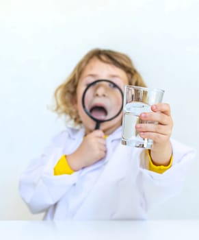 A child examines water with a magnifying glass. Selective focus. kid.