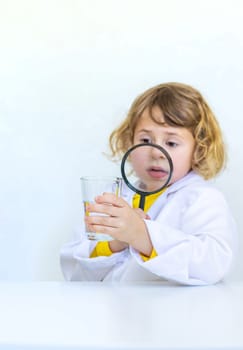 A child examines water with a magnifying glass. Selective focus. kid.