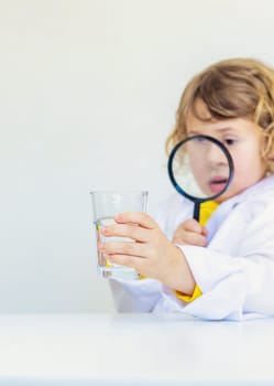 A child examines water with a magnifying glass. Selective focus. kid.