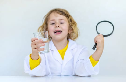 A child examines water with a magnifying glass. Selective focus. kid.