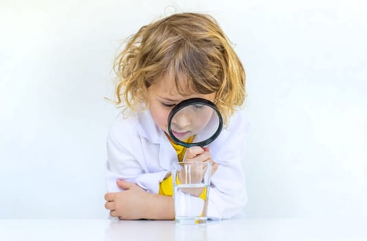 A child examines water with a magnifying glass. Selective focus. kid.