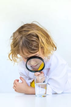 A child examines water with a magnifying glass. Selective focus. kid.