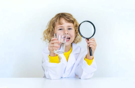 A child examines water with a magnifying glass. Selective focus. kid.