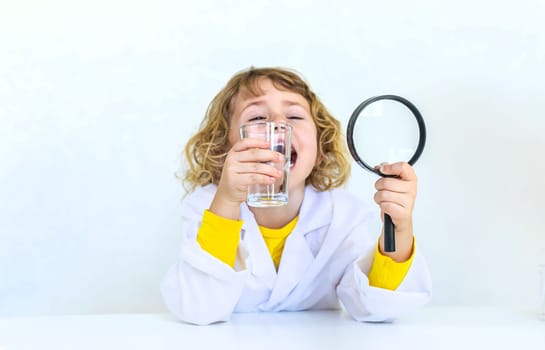 A child examines water with a magnifying glass. Selective focus. kid.