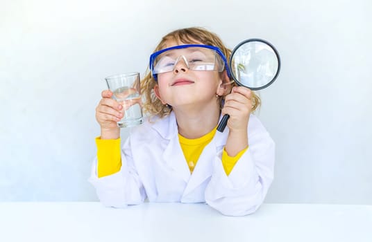 A child examines water with a magnifying glass. Selective focus. kid.