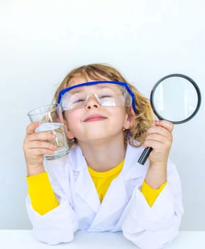 A child examines water with a magnifying glass. Selective focus. kid.