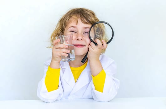 A child examines water with a magnifying glass. Selective focus. kid.