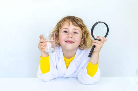 A child examines water with a magnifying glass. Selective focus. kid.