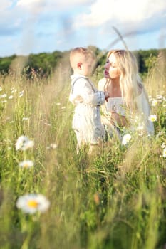 Mother and little child in a meadow with daisies resting and chatting. High quality photo