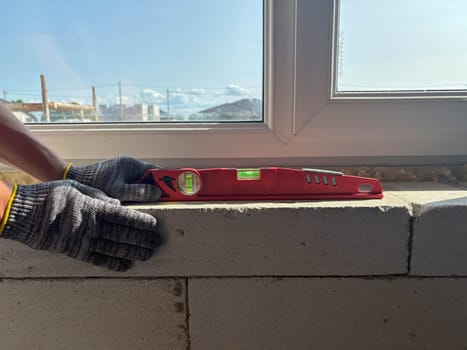 A building level on a window sill during house construction. The builder checks the level of the window sill. Construction and renovation of housing.