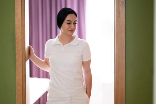Female Therapist Smiling at Doorway. A female therapist stands at the doorway, smiling warmly, ready to welcome the next patient.