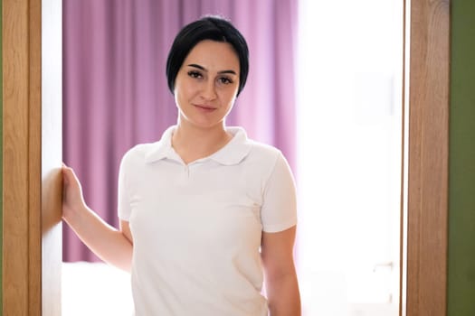 Female Therapist Smiling at Doorway. A female therapist stands at the doorway, smiling warmly, ready to welcome the next patient.