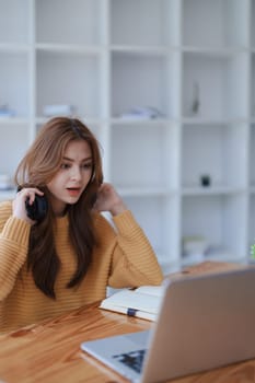A young woman looks surprised while working on her laptop at home office..
