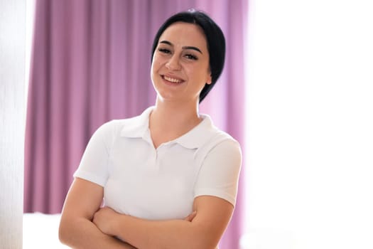 Confident Female Healthcare Worker. Portrait of a confident young female healthcare worker in a white uniform standing with arms crossed.