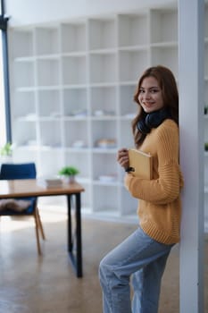 Young woman with headphones holds book in bright modern office space ..
