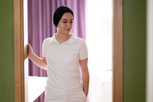Female Therapist Smiling at Doorway. A female therapist stands at the doorway, smiling warmly, ready to welcome the next patient.