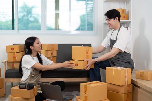 In a cozy home office, a couple collaborates as one partner hands a box to the other, emphasizing teamwork and connection.