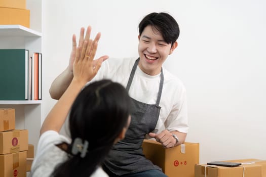 A couple enjoying their time together while managing a small business, surrounded by boxes and a laptop, showcasing teamwork and happiness.