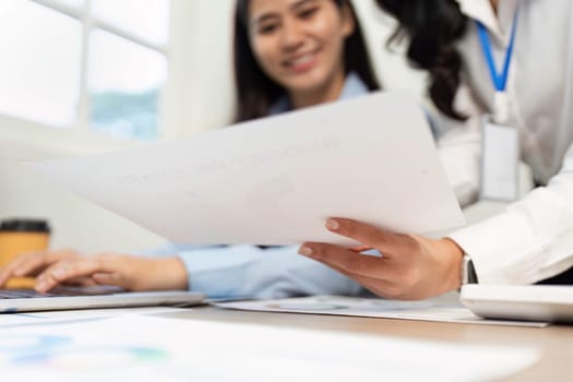 Two women analyzing reports together, showcasing teamwork and effective communication in a professional setting.