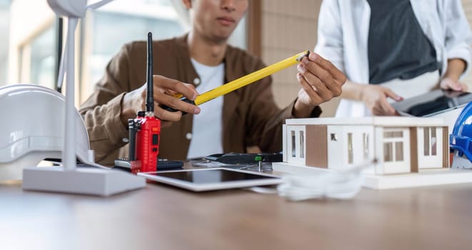 An architect measures materials while discussing sustainable building practices, emphasizing ESG and innovation.