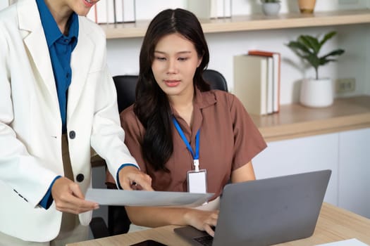 Professional women engage in a collaborative discussion over documents in a stylish office environment, highlighting teamwork and productivity.