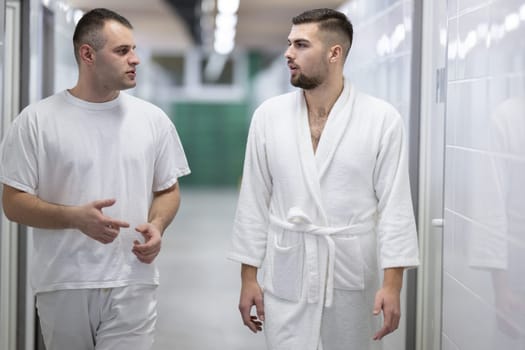 Medical Consultation in Spa Corridor.Two men discussing treatment options while walking through a clinical spa corridor, wearing white uniforms and bathrobe