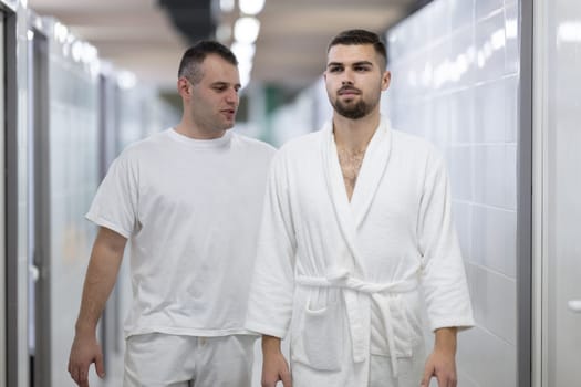 Medical Consultation in Spa Corridor.Two men discussing treatment options while walking through a clinical spa corridor, wearing white uniforms and bathrobe