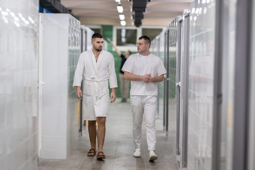 Medical Consultation in Spa Corridor.Two men discussing treatment options while walking through a clinical spa corridor, wearing white uniforms and bathrobe