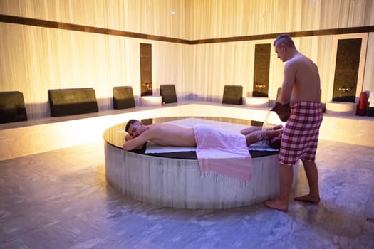 Water Treatment in Turkish Hammam.Man receiving water therapy inside a traditional Turkish hammam with ornate details.